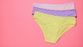 Neatly stacked stack of women`s panties on a pink background. Fashionable concept. Beautiful lingerie