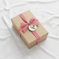 A neatly wrapped gift box rests on a smooth white fabric surface Royalty Free Stock Photo