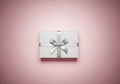 A neatly wrapped rectangular gift box with a smooth silver ribbon and bow is set against a soft Royalty Free Stock Photo
