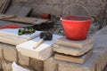 Necessary tools for construction - rubber hammer, bucket and gloves. Construction site in full swing. Discarded tiles. Workers