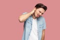 Neck or back pain. Portrait of sad sick handsome bearded young man in blue casual style shirt standing and holding his painful Royalty Free Stock Photo