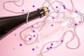 Neck of a bottle of champagne and a glass on a pastel pink background. Royalty Free Stock Photo