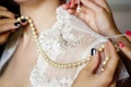 Neck and breast of bride in lace wedding dress and hands of bridesmaids with pearl necklace and chain Royalty Free Stock Photo