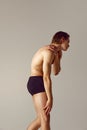 Neck and hand pains. Shirtless young man with fit body standing in underwear against grey studio background Royalty Free Stock Photo