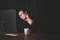 Neck pain or tired concept. Man touching his neck because pain or hurt after long time working on computer in the dark room at