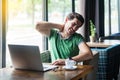 Neck pain. Young sick businessman in green t-shirt sitting and working on laptop and feeling pain ache on his neck or back after Royalty Free Stock Photo