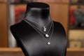 Necklaces made of white gold with diamonds on a stand in fashion jewelry boutique. Black stand neck with luxury jewelry, women
