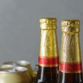 Necks of beer bottles with gold labels and cans. The necks of the bottles close up