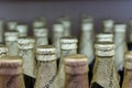 The necks of beer bottles wrapped in foil and displayed in a row. Packing of alcohol bottles