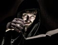 Necromancer casts spells from thick ancient book by candlelight on a dark background Royalty Free Stock Photo