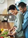 Need a hand...an affectionate young couple preparing a meal together in their kitchen. Royalty Free Stock Photo