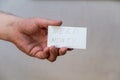 Need money. Words written in jagged letters. A man`s hand holds a white paper rectangle with text against a gray background Royalty Free Stock Photo