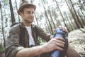 Optimistic hiker is holding vacuum flask in forest