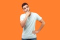 Need to think. Portrait of thoughtful brunette man holding his chin and pondering idea. indoor studio shot isolated on orange