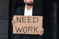 Need work. Unrecognizable male office worker holding cardboard sign, standing outdoors near business center, crop Royalty Free Stock Photo