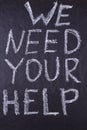 WE NEED YOUR HELP handwritten iscription with a chalk on black chalkboard.