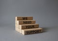 We need your support symbol. Wooden blocks with words We need your support. Beautiful grey background. Business and We need your