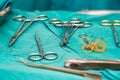 Needle holders with needles and sutures and scissors on operating table in surgical procedure.