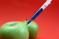 A needle for injection is stuck in a green apple Royalty Free Stock Photo