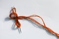 Needle and orange thread on white paper surface