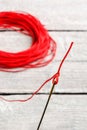 Needle with red thread, focus on the eye of a needle, on wooden background Royalty Free Stock Photo
