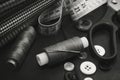 A needle with thread, buttons and scissors lie on a wooden background. Black and white photo Royalty Free Stock Photo