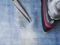Needle and thread, scissors and iron on the background of the protection of the denim. Repair of jeans at home.