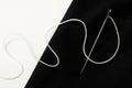 Needle with white thread on black fabric. Royalty Free Stock Photo