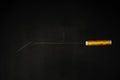 A needle with yellow thread threaded together with a spool of the same material on a black background Royalty Free Stock Photo
