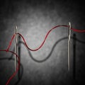 Needles vertically oriented are threaded with a single red thread Royalty Free Stock Photo
