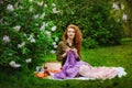 Needlework in the garden. Young woman crocheting sitting on the grass in the park. Picnic and leisure, knitting in nature