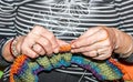 Hands of old woman holding knitting needles and multi colored wool for woolwork of warm sweater for cold winter days close up sele Royalty Free Stock Photo