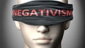 Negativism can make things harder to see or makes us blind to the reality - pictured as word Negativism on a blindfold to