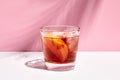 Negroni cocktail over pink background. Drink in rox glass in daylight with palm leaf hard shadow. Summer, tropical, fresh drink Royalty Free Stock Photo