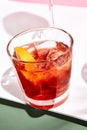 Negroni cocktail over pink background. Drink in rox glass in daylight with palm leaf hard shadow. Summer, tropical, fresh drink Royalty Free Stock Photo