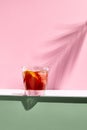 Negroni cocktail over pink background. Drink in rox glass in daylight with palm leaf hard shadow. Summer, tropical, fresh drink Royalty Free Stock Photo