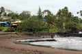 A neighborhood, picnic area and beach of Hana Bay with a man, dog and toddler walking on the beach, Maui Royalty Free Stock Photo