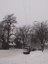 Neighborhood street with snow, parked cars and bare trees. Winter weather. Royalty Free Stock Photo