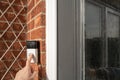 Neighbour seen pressing a popular, wireless smart door bell at the front of the house, outside the porch.