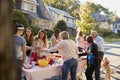 Neighbours talk standing around a table at a block party Royalty Free Stock Photo