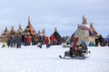 Nenets women go on a snowmobile among tents