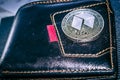 Neo cryptocurrency coin on leather wallet.