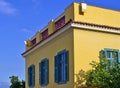 Neoclassical architecture yellow house with windows with blue shutters against clear sky Royalty Free Stock Photo