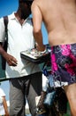 Salesman on the beach selling earphones, watches, and purses to customer