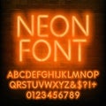 Neon alphabet font. Simple orange neon letters and numbers. Brick wall background.