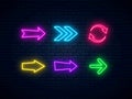 Neon arrow signs set. Bright arrow pointer symbols on brick wall background. Collection of colorful neon arrows Royalty Free Stock Photo