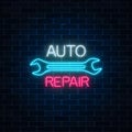 Neon auto repair shop sign on dark brick wall background. Glowing night advertising symbol.