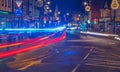 Neon bright Night trail of cars and ambulance in town road England