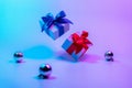 Neon Christmas winter background. Xmas gift box with shine lights. Holiday gifts, decoration bauble ball on neon Royalty Free Stock Photo