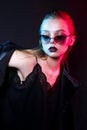 Neon close up portrait of young woman in sunglasses. Model posing in red and blue light